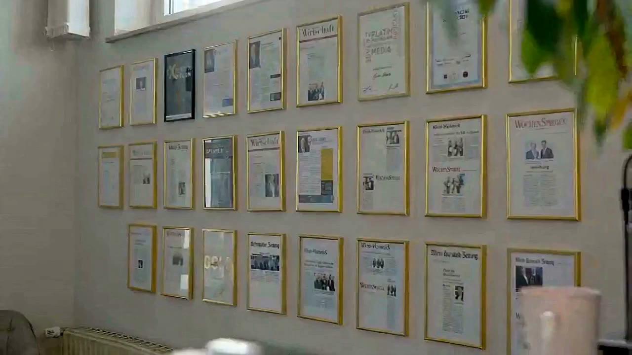 Wand mit gerahmten Presseartikeln im Büro von Novitas